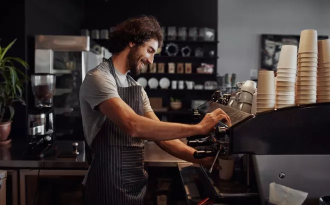 Glimlachende student werkt als barista in een koffiebar